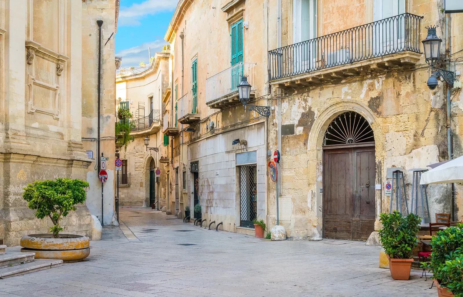 Alleyway of a town with outdoor seats and yellow buildings