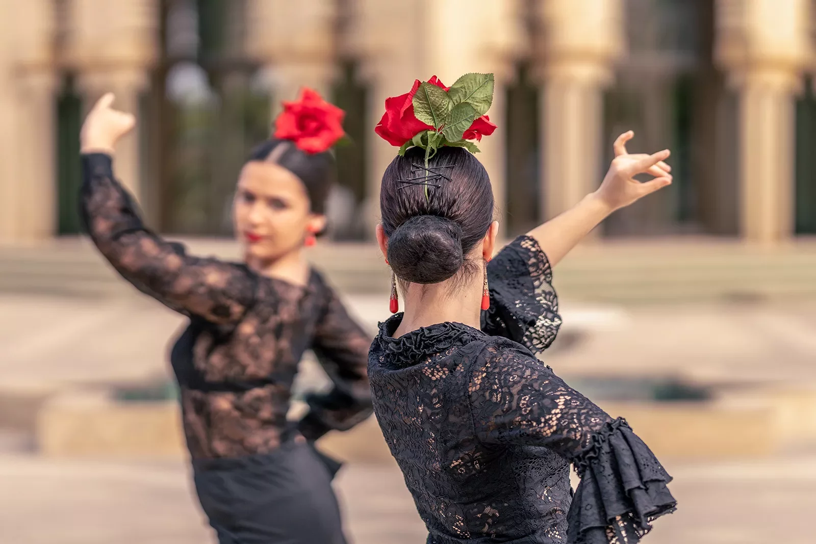 Two women dancing with large red roses on their heads
