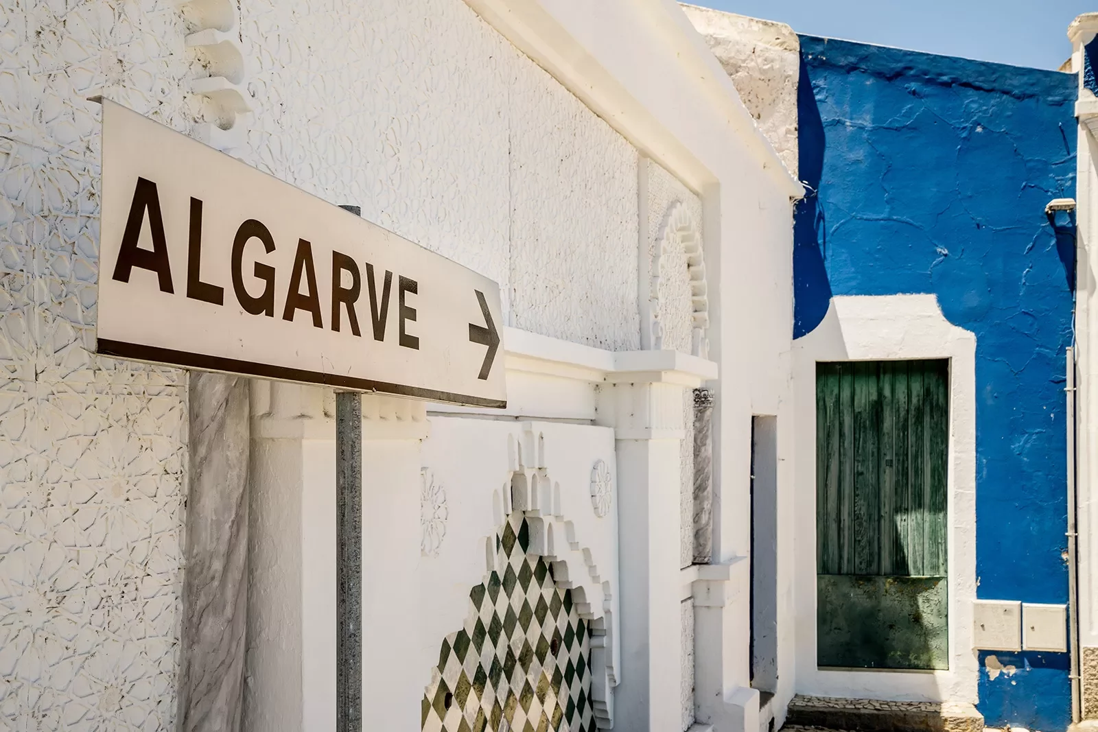 A sign pointing to a blue building with the word &quot;Algarve&quot;