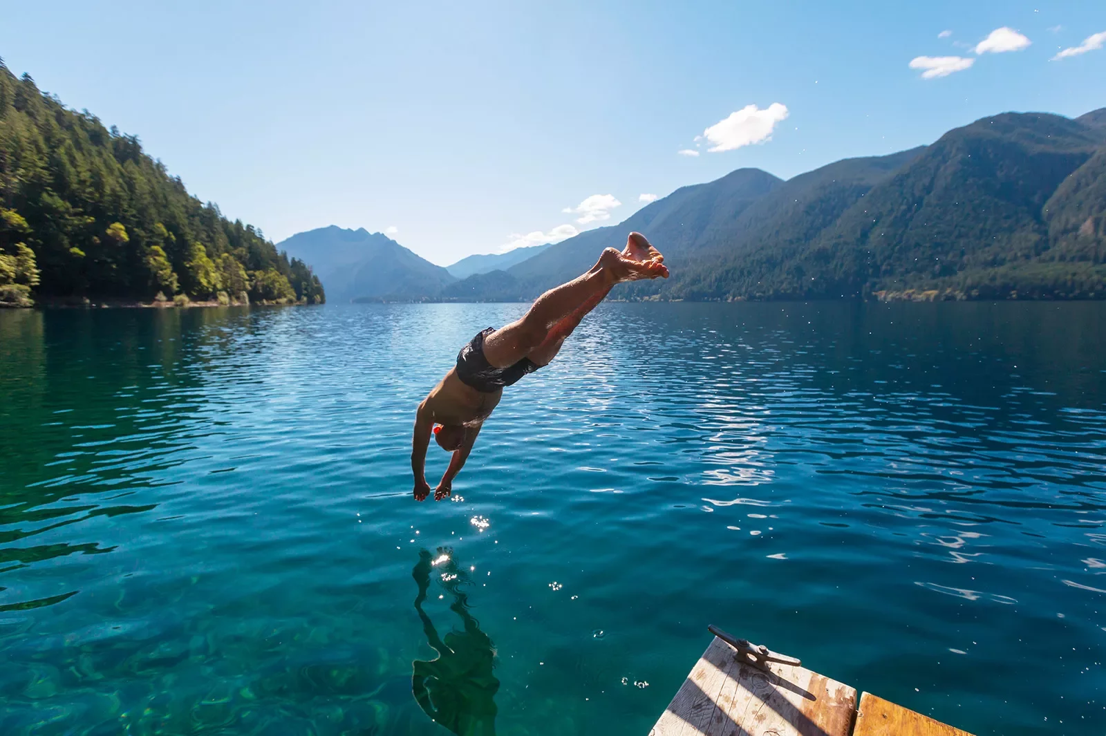 Man diving into a lake from a wooden port