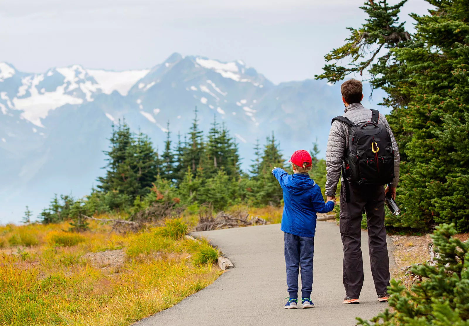 Man and child pointing at snow-capped mountains in the distance