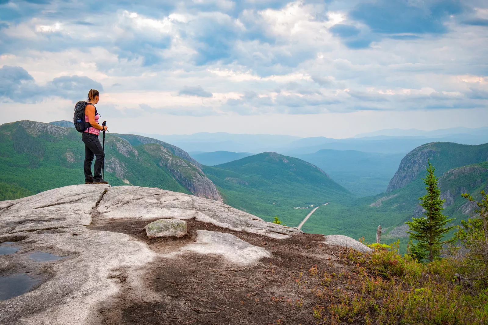 Woman at the top of a rock looking down at grassy hills