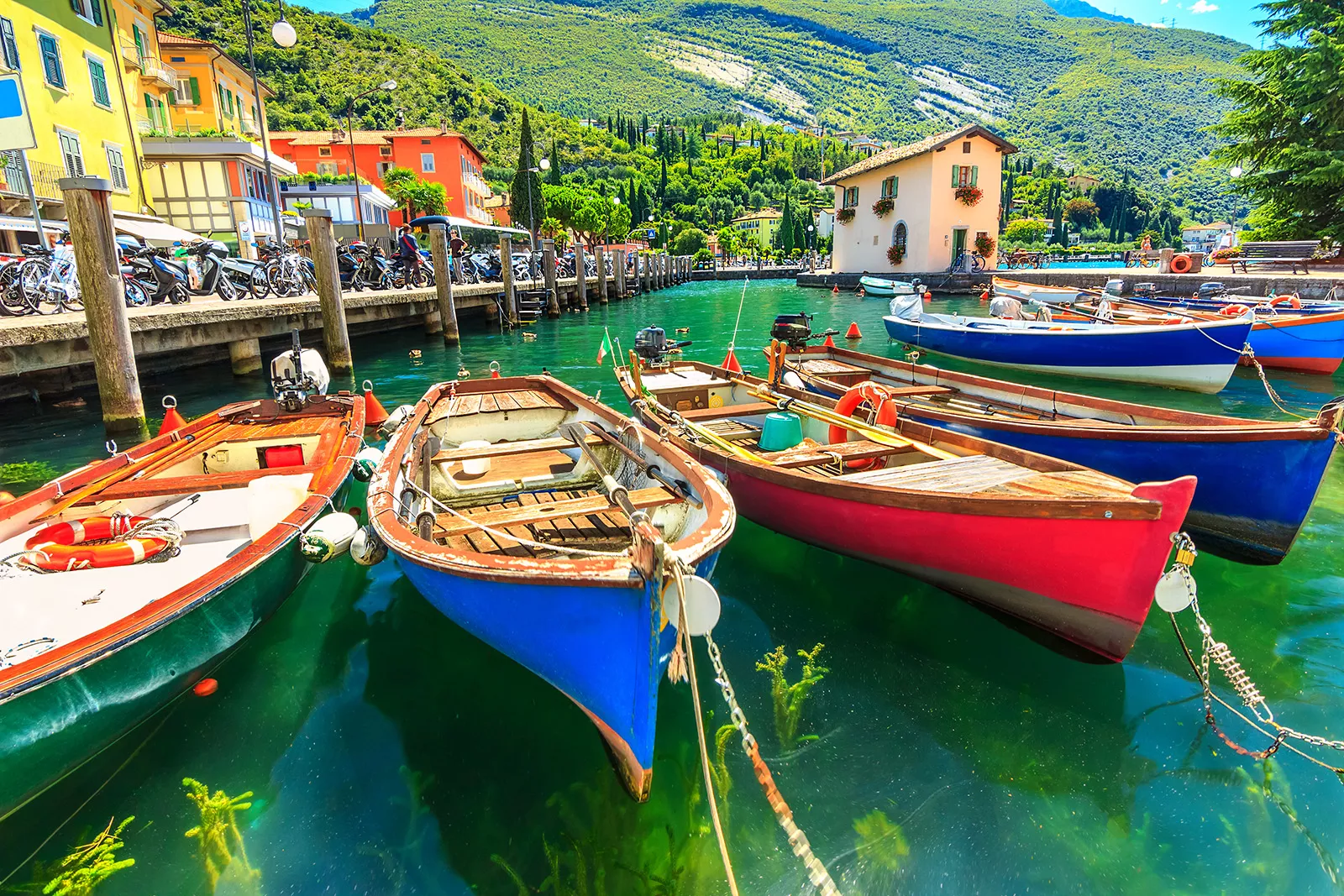 Multiple colorful boats tied to a dock by the ocean