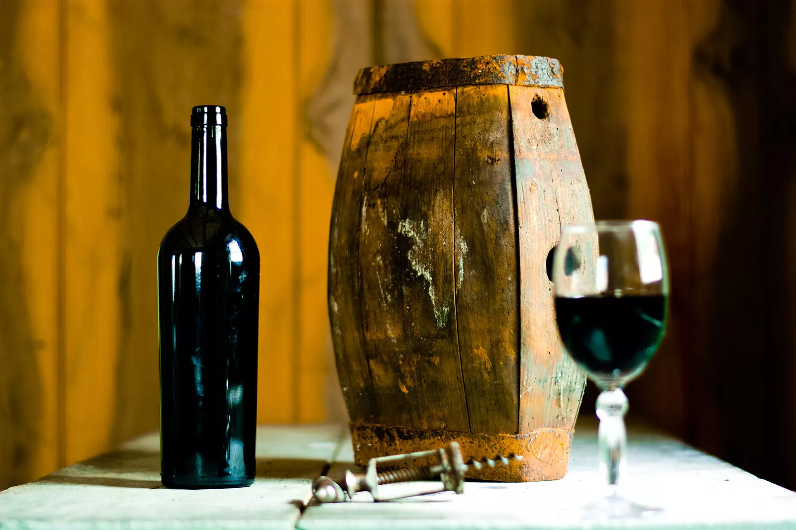 Barrell next to an open bottle of wine and a wine glass