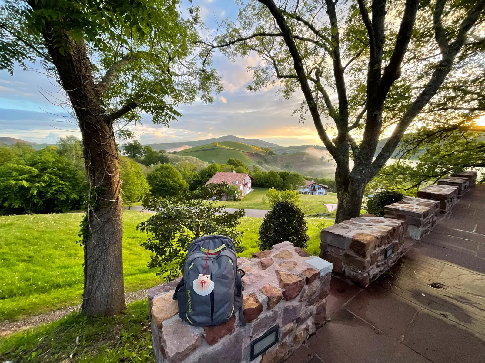 Backpack sitting on a stone block, overlooking a grass valley and small town buildings