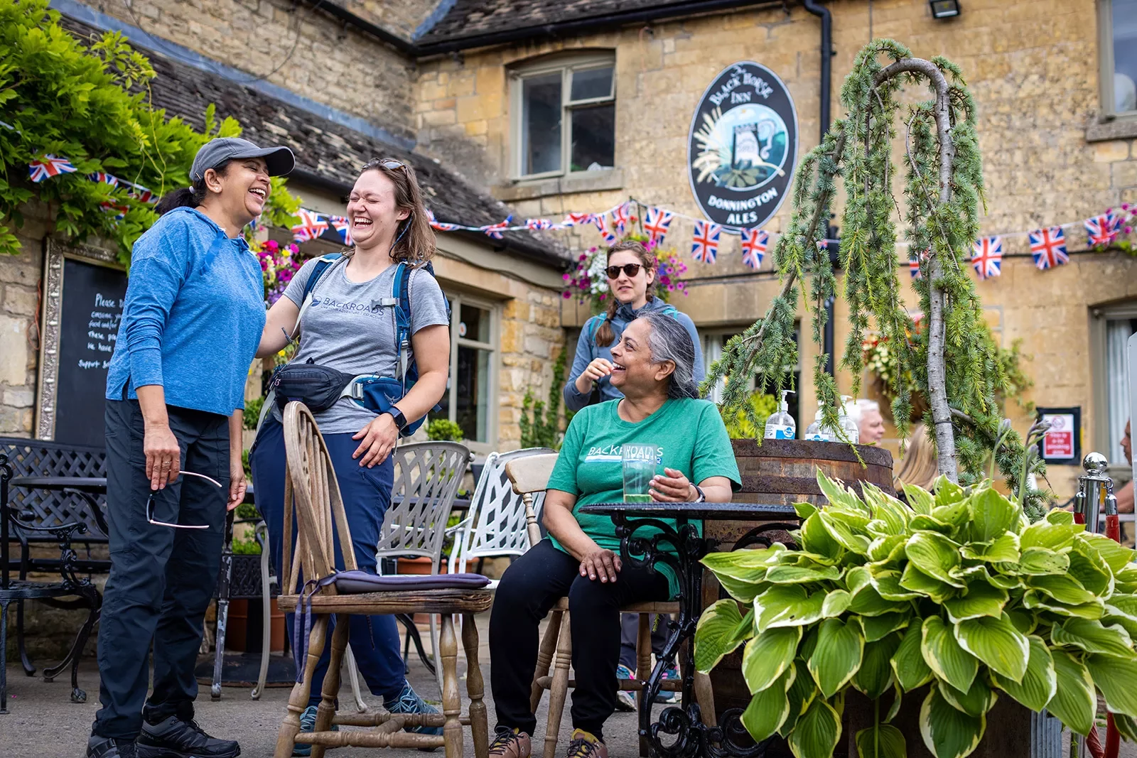 Four women laughing and smiling in an outdoor patio