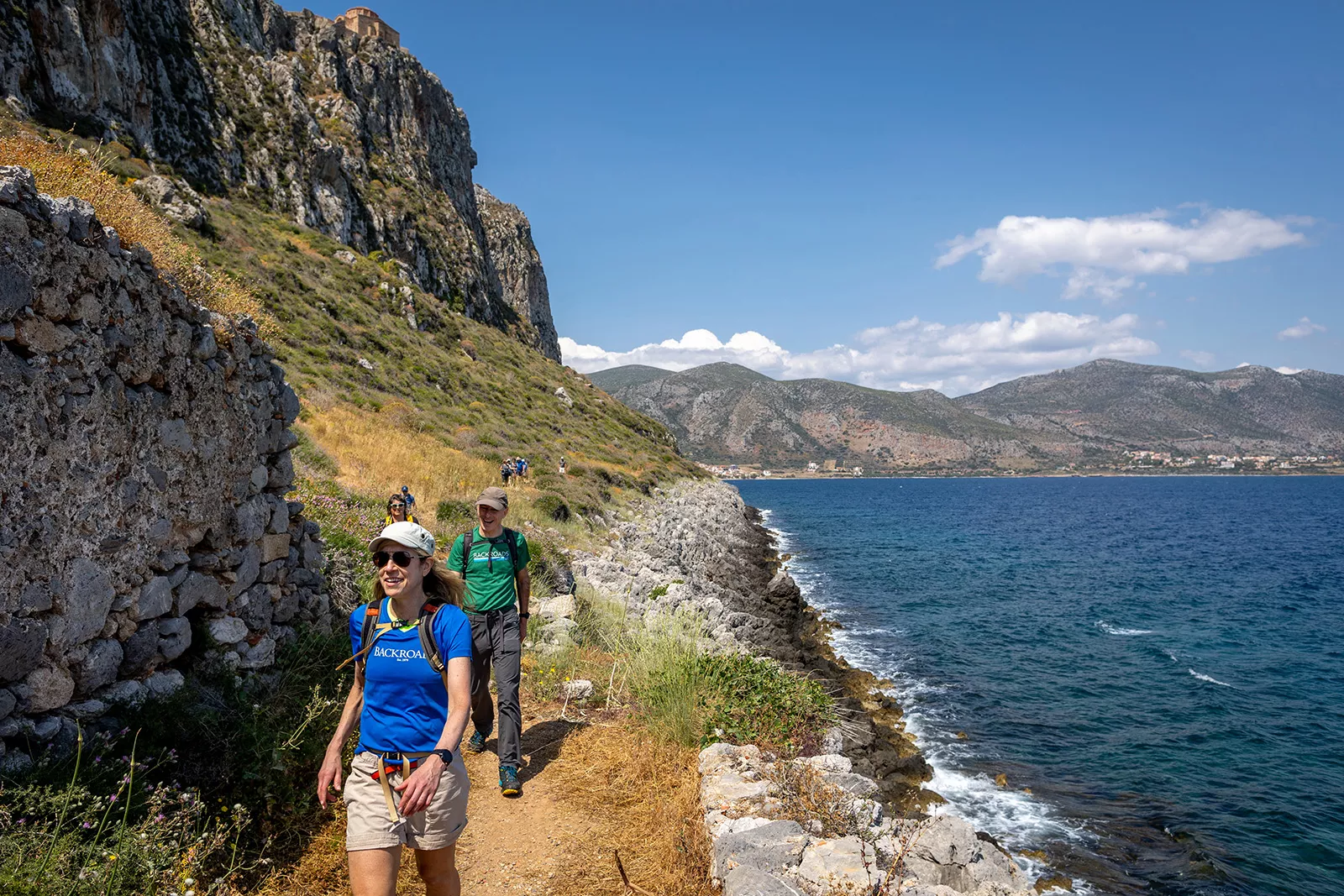 Group of people hiking on a gravel path next to the ocean