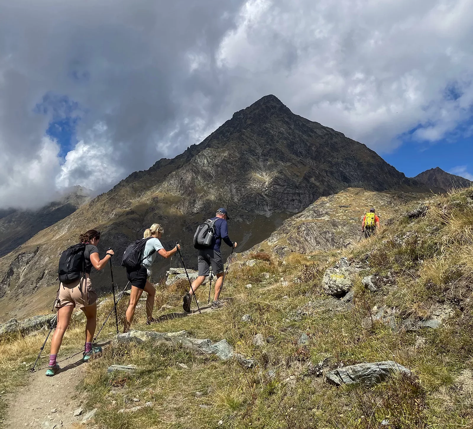 Four people with walking sticks hiking up a mountain