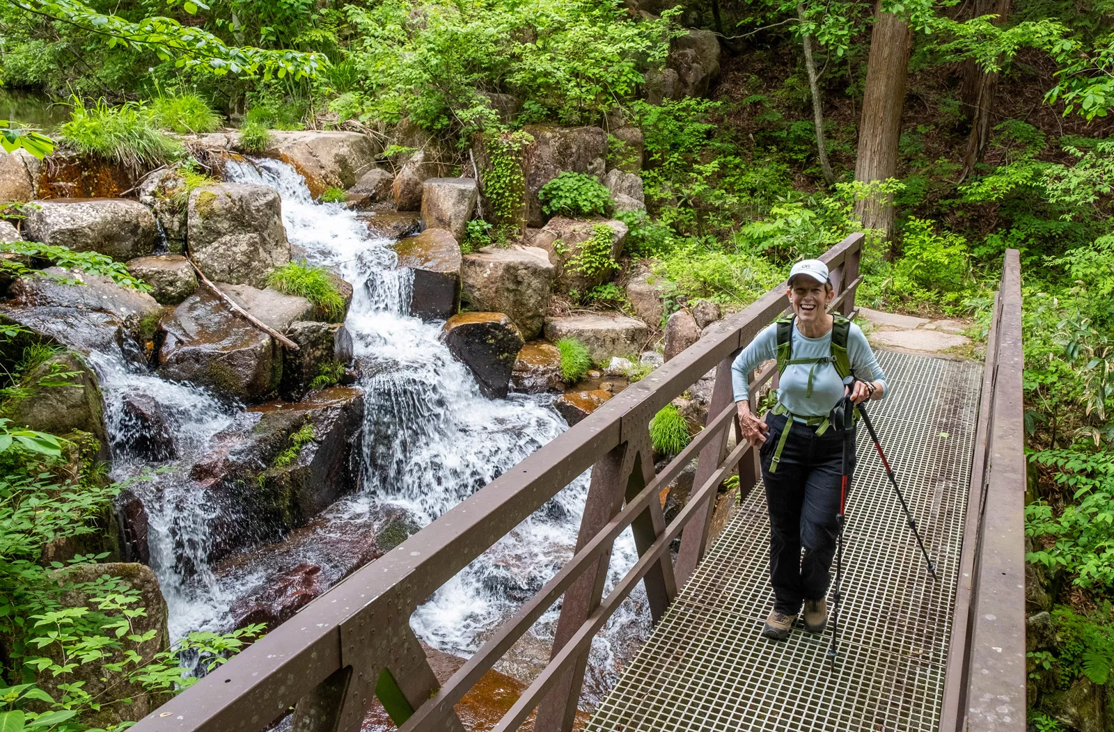 Woman standing on a bridge in front of a waterfall