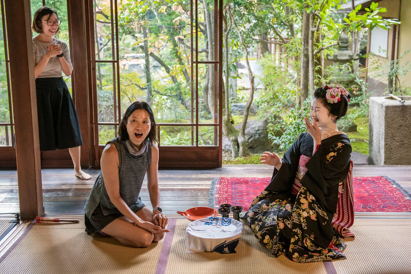 Woman sitting in front of a geisha, kneeling on the ground