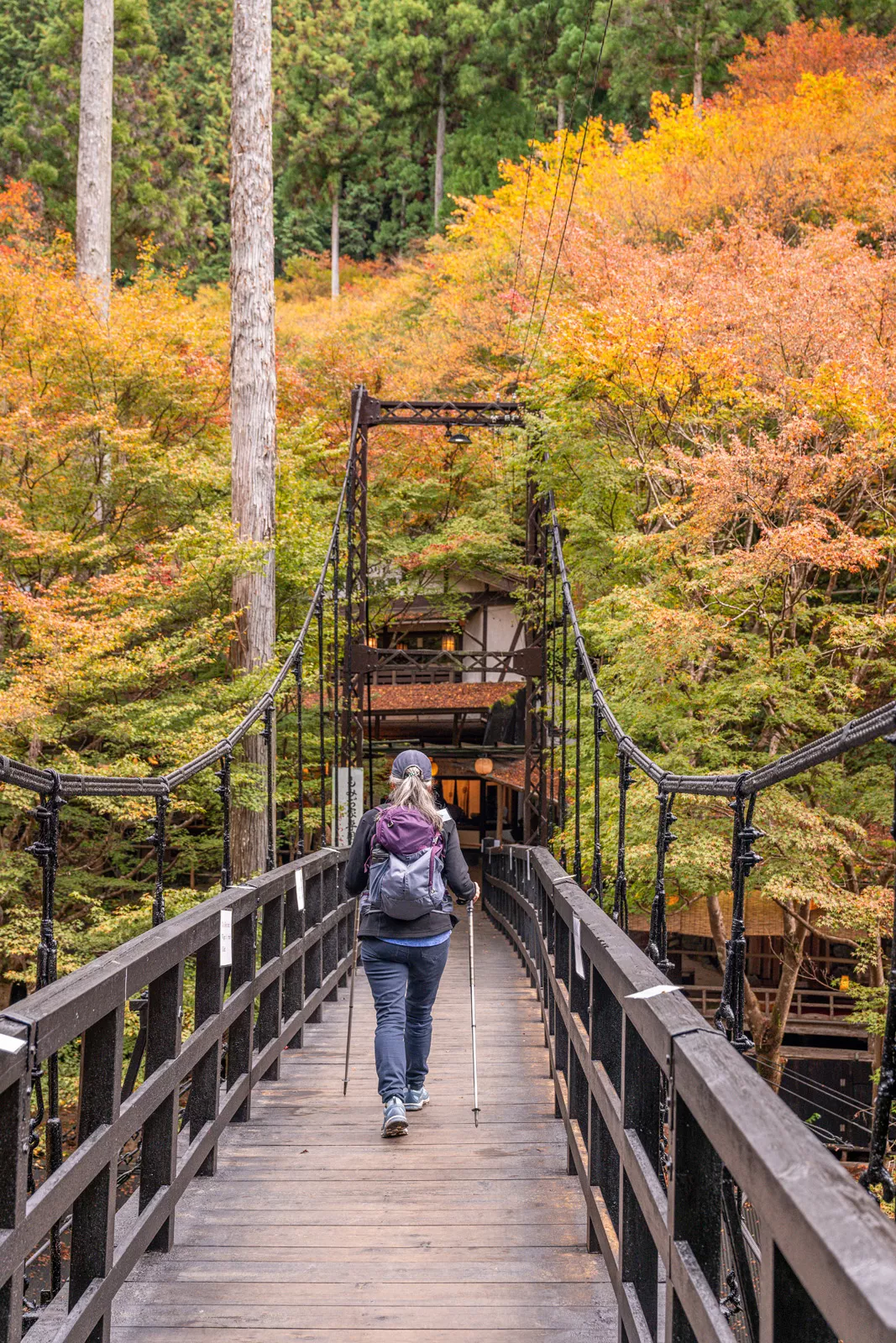 Woman with hiking poles crossing a bridge