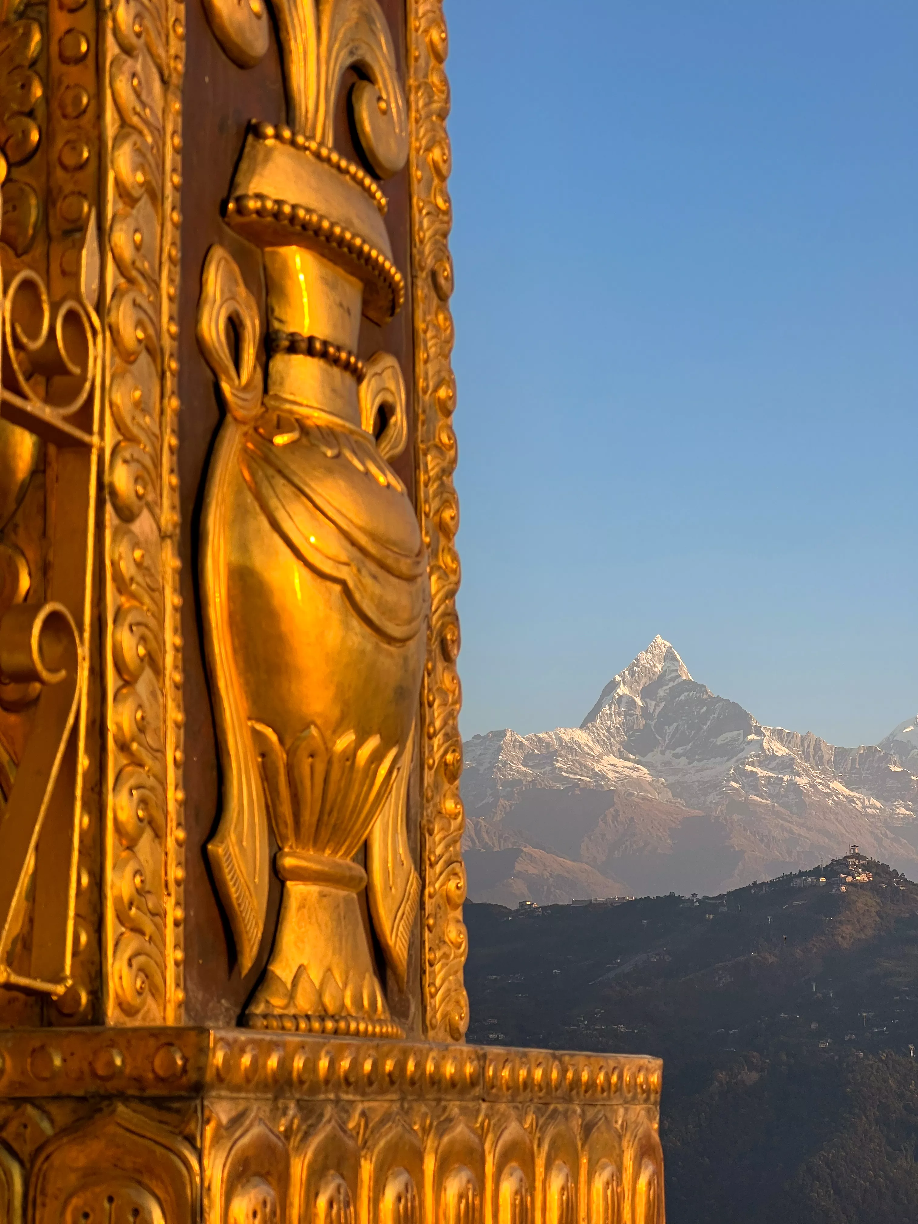 Copper statue of a traditional vase with snowy mountains in the distance