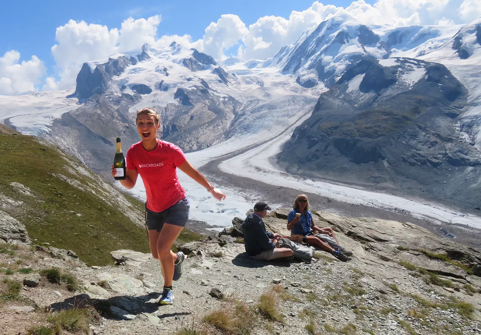 Woman holding a bottle of wine ascending a mountain