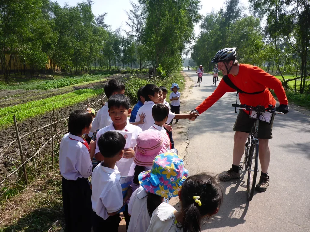 Backroads biker stopping to talk to children in Vietnam