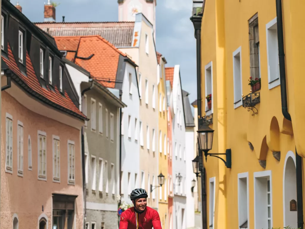 Man in red riding a bicycle in an alley of a European town