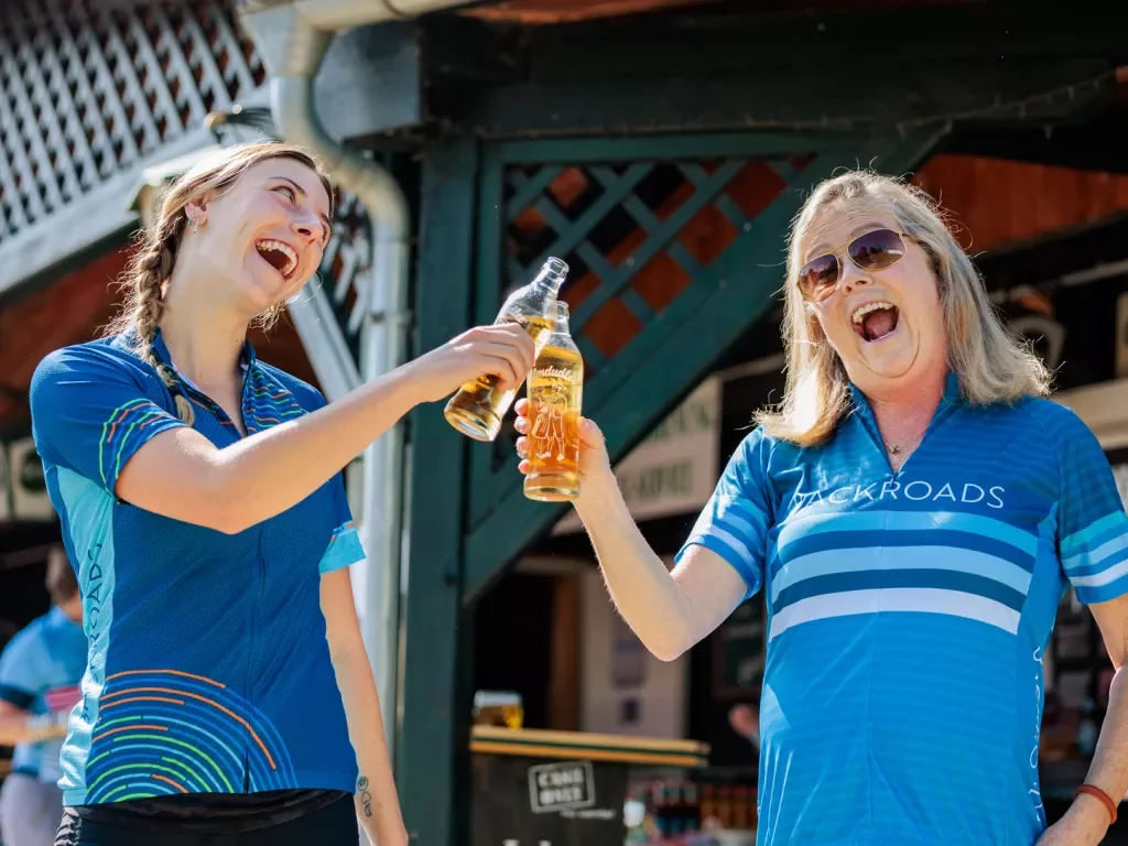 Two woman clinking their bottles of drinks and smiling