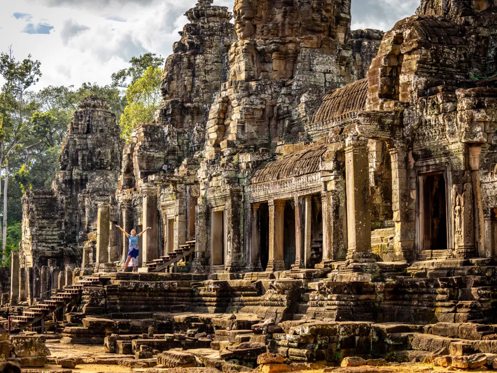 Woman with arms open next to ancient temple ruins