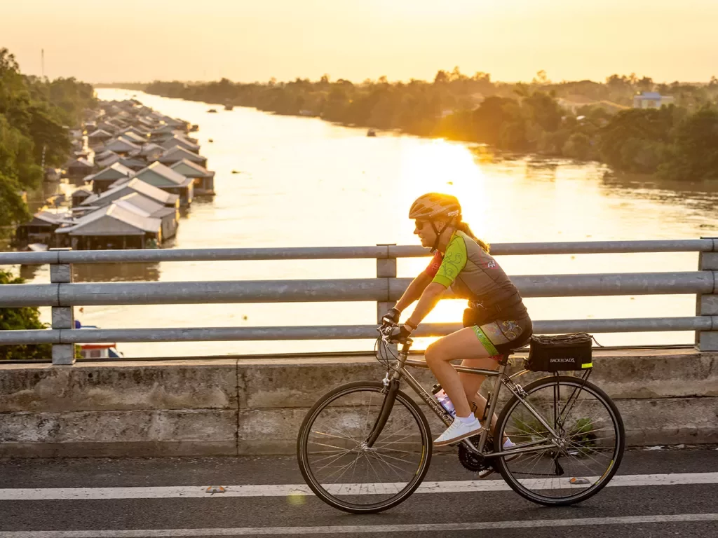 a cyclist on a bridge at sunset
