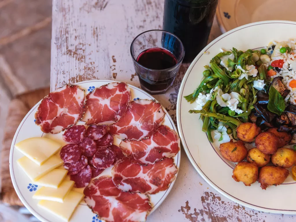 Plates full of cured meats, cheeses and salad
