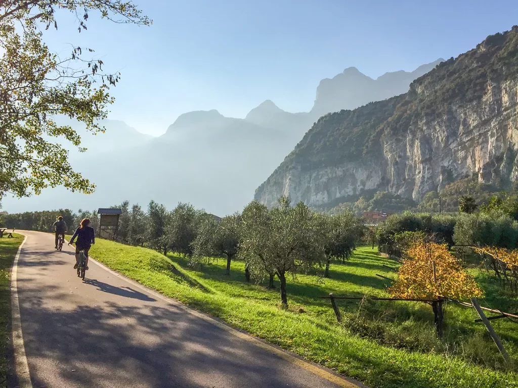 Two bikers on a road through grassy fields