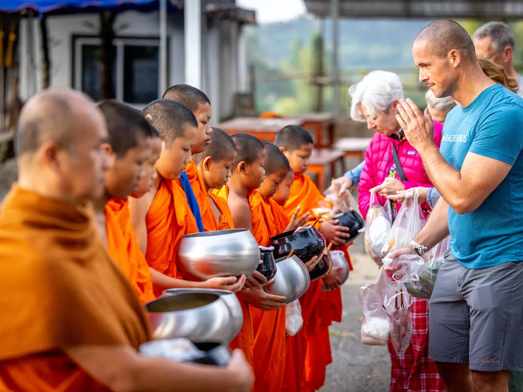 Group of people praying in front of monks with orange robes