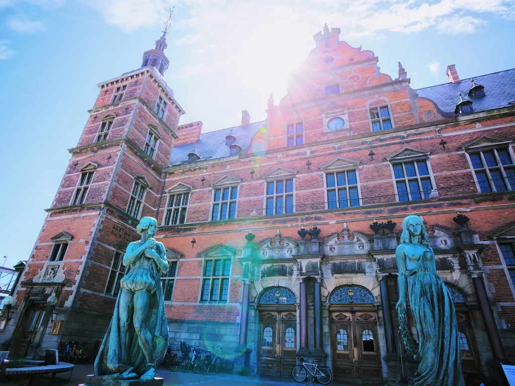 Rustic, red brick building with two blue statues outside