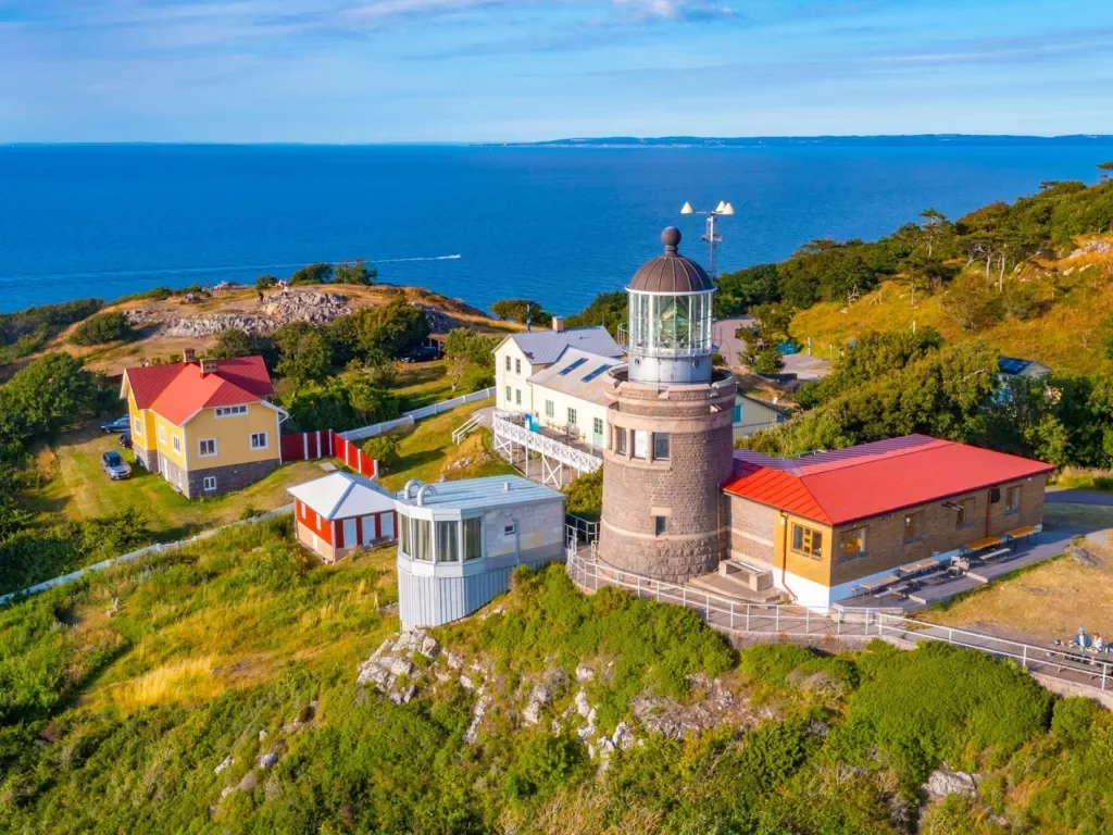 Lighthouse building with smaller buildings and the ocean in the distance