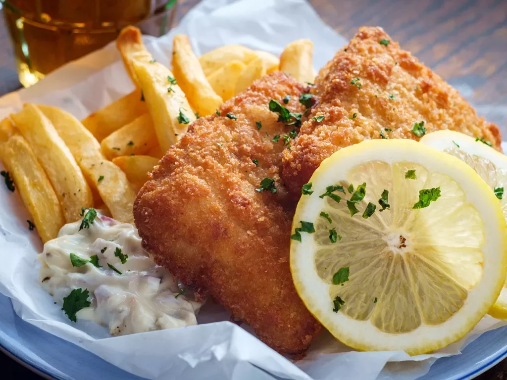 A plate of fish and chips with two slices of lemon