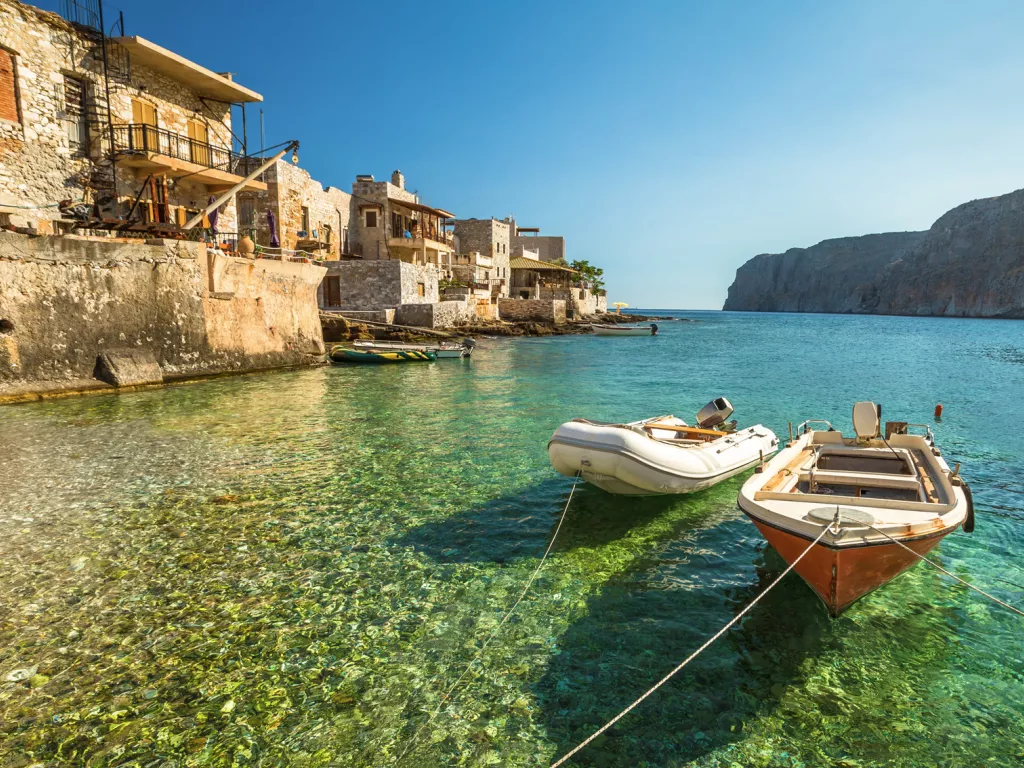 Two small boats tied to a dock with rustic buildings in the background