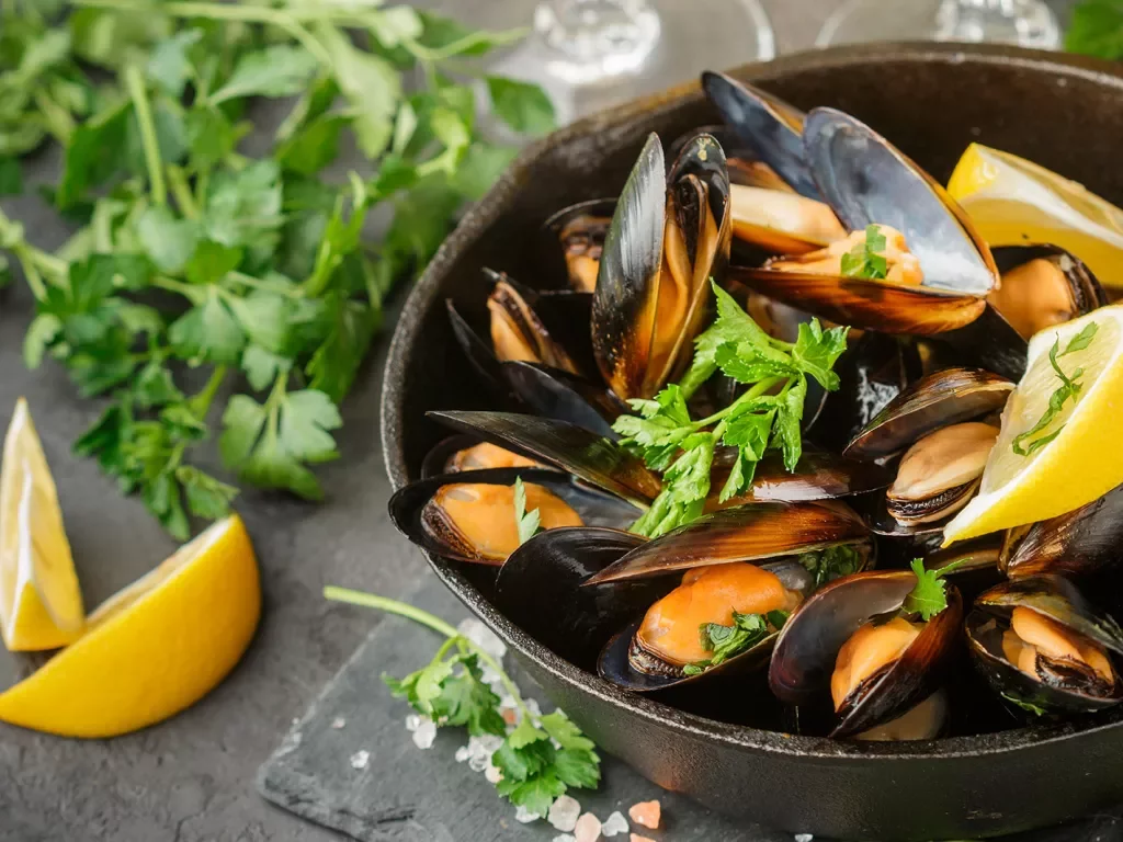 Bowel of cooked mussels with lemons and parsley