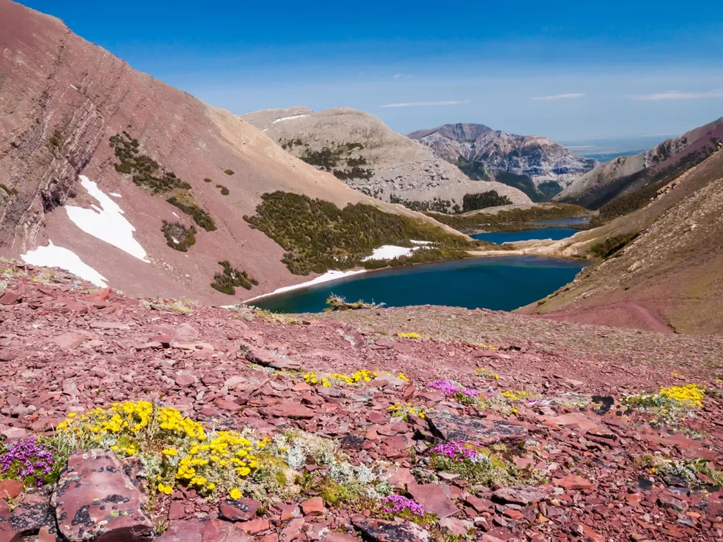 Pink and red rocks on a hill with a lake in the distance