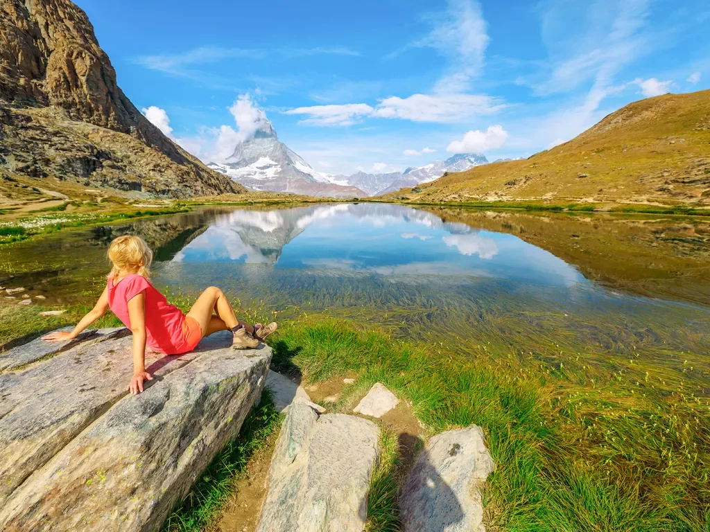 Girl sitting on a rock looking out to a lake and valleys