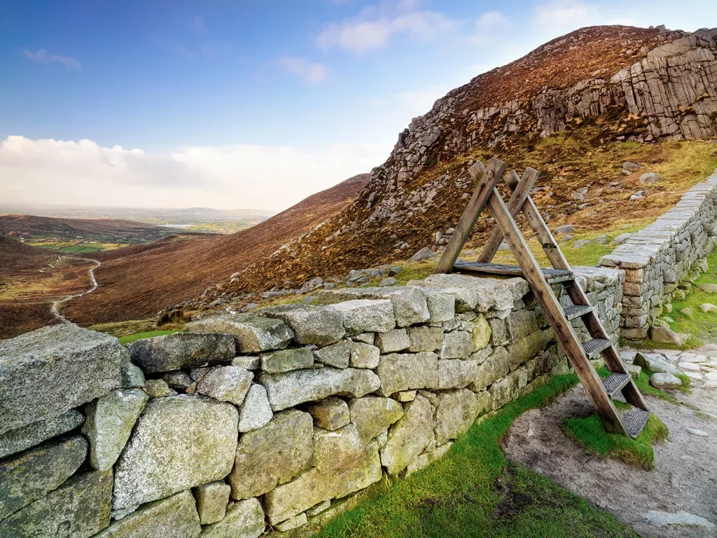 Small wooden latter over a stone barricade overlooking an empty valley