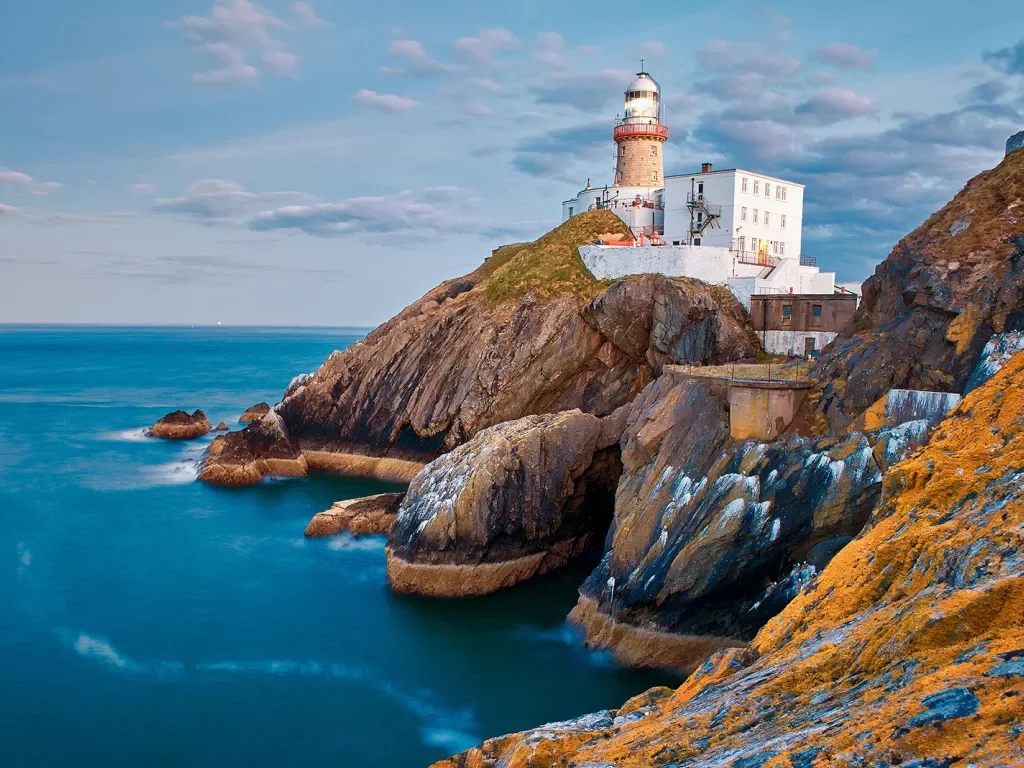 Lighthouse buildings on top of a cliff next to the ocean