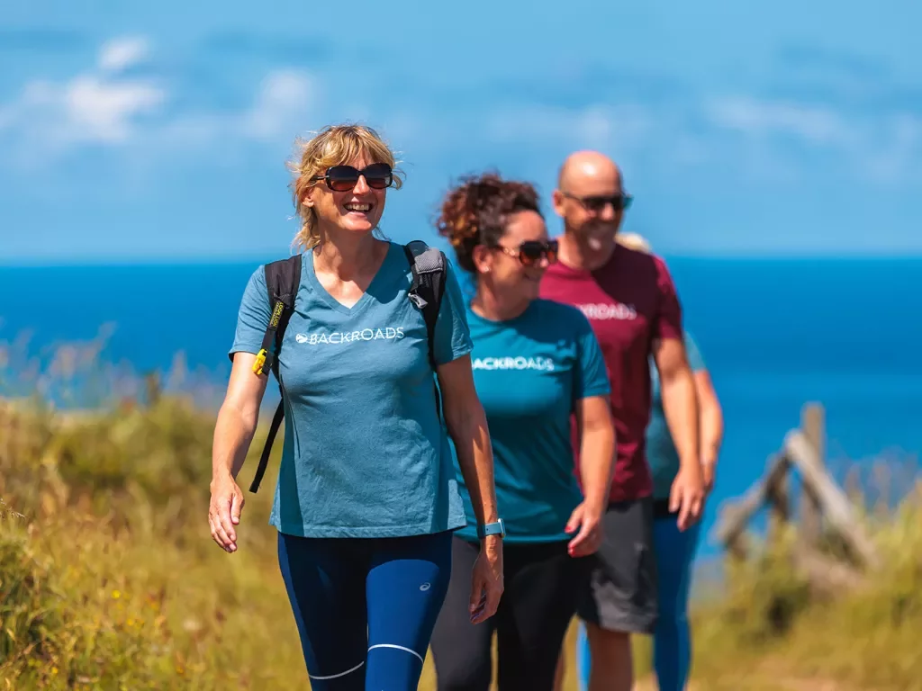 Two women and one man walking on a trail