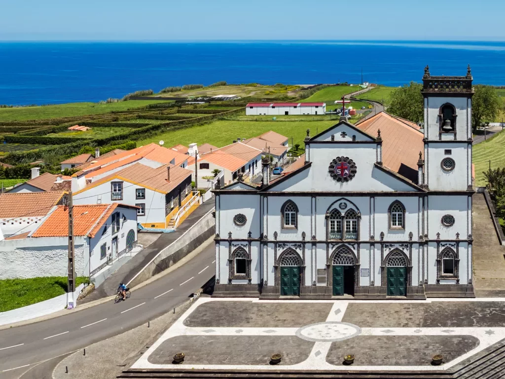 Large church building in the middle of a small town, with an ocean in the background