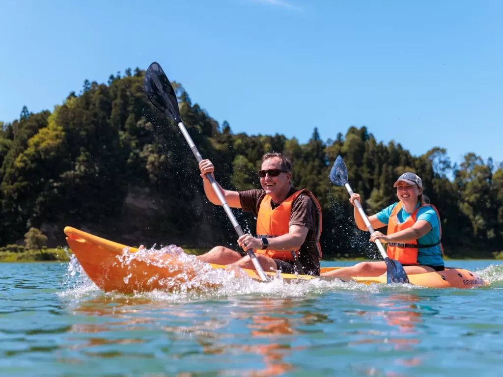 Man and woman smiling in a kayak while paddling in the middle of a lake