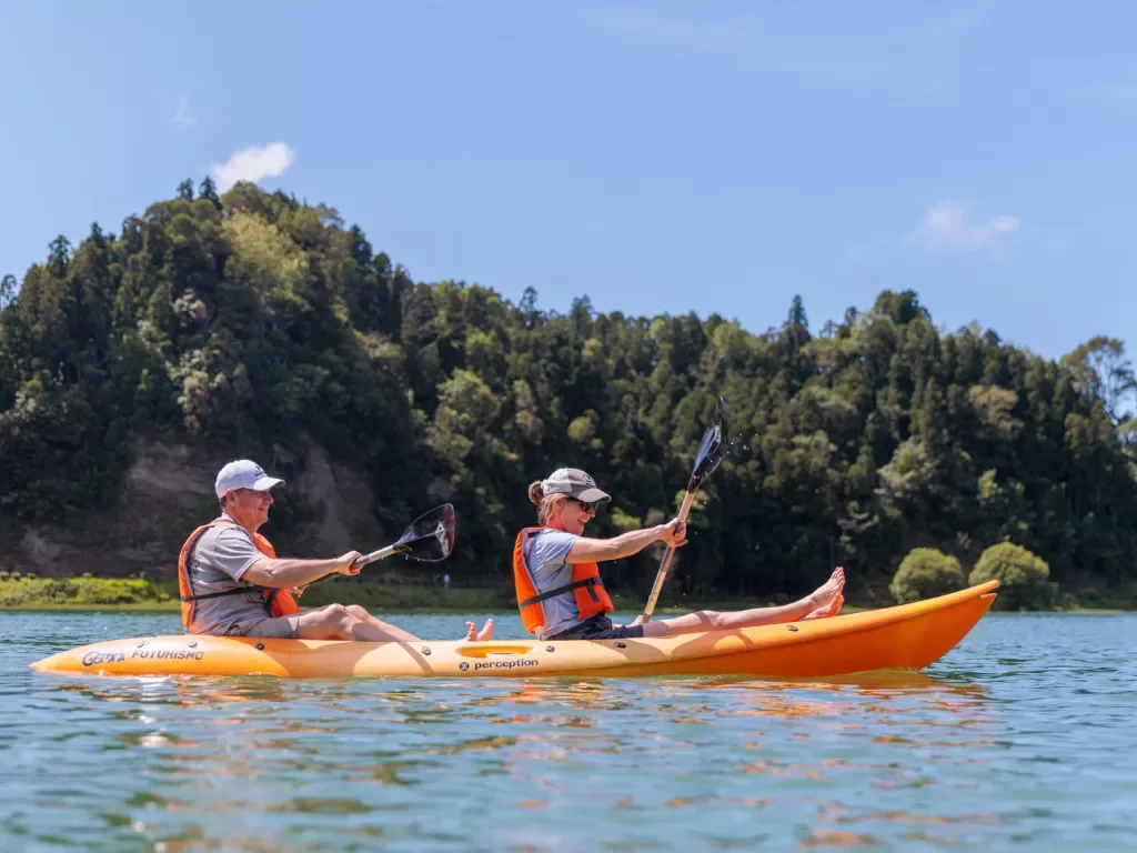 Man and woman inside of a kayak, paddling in the middle of a lake