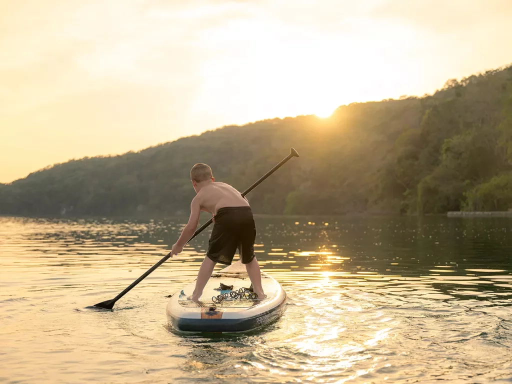Child paddle boarding in the middle of a lake