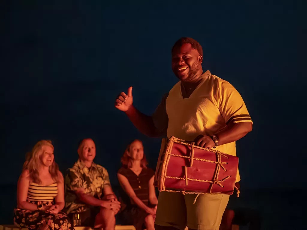 Man holding bongo with a group of people behind him