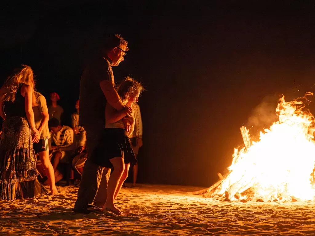 Father and daughter looking at a campfire