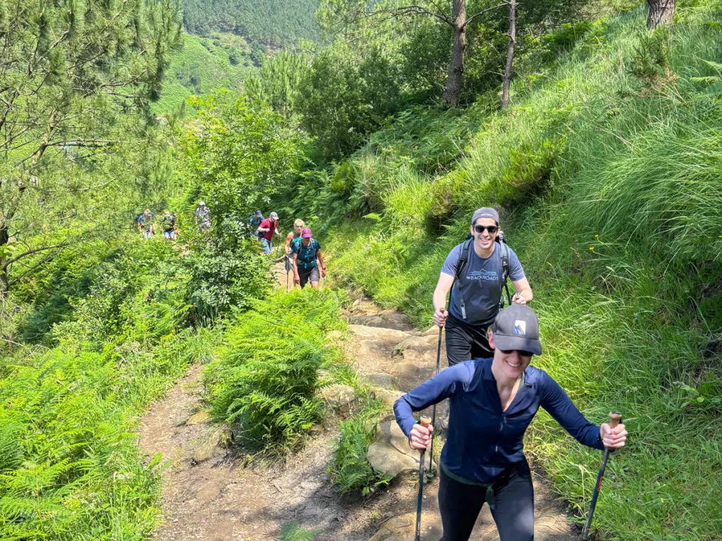 Group of hikers with walking poles ascending up a rocky trail