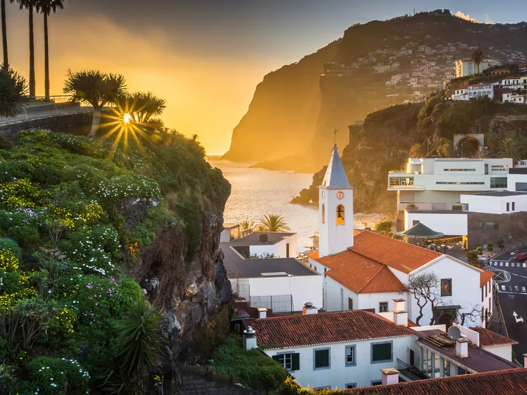 Sunset hitting a small town, filled with white and red buildings on cliffs