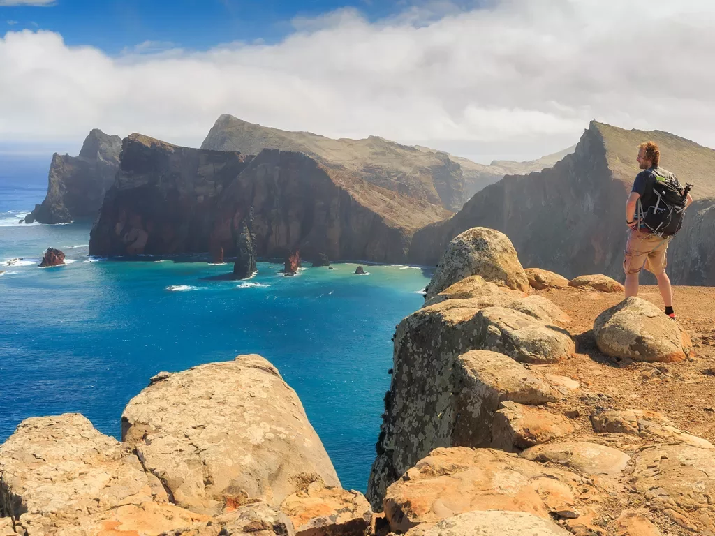 Man close to the edge of a cliff looking down at the ocean