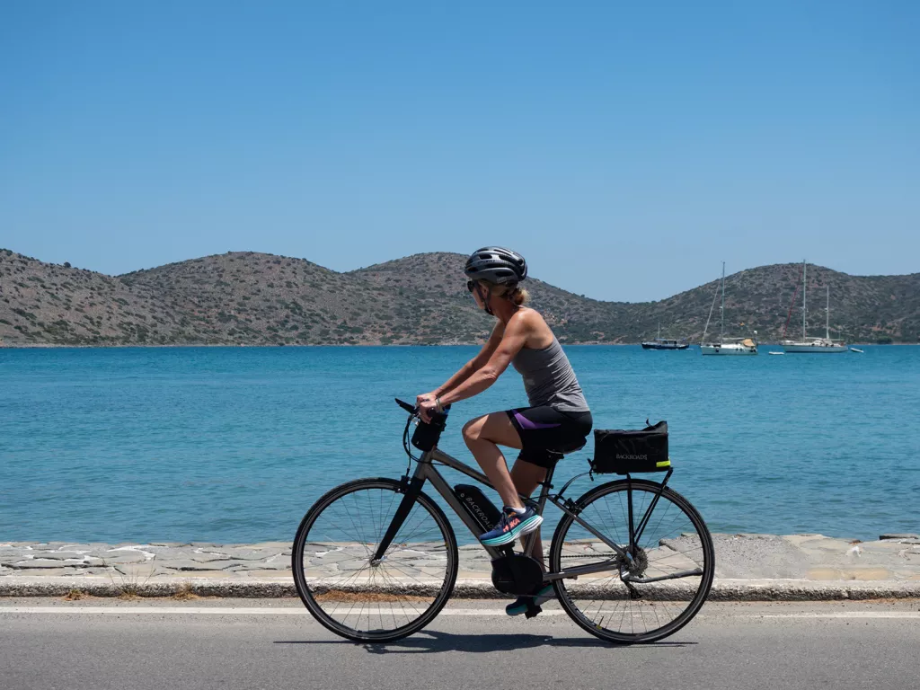 Woman on an e-bike along a road next to the ocean