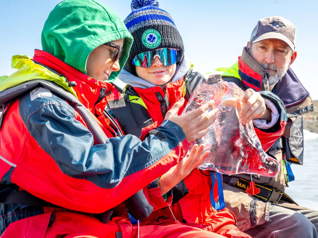 Two boys holding a large, clear block of ice