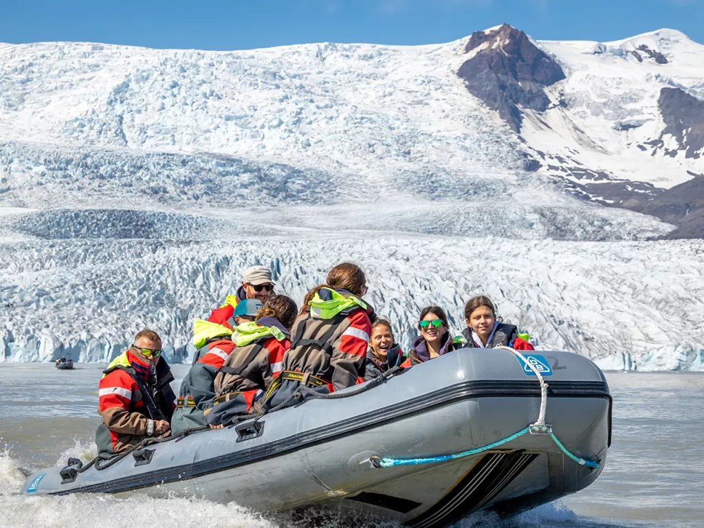 Group of people on a gray raft with snow mountains in the background