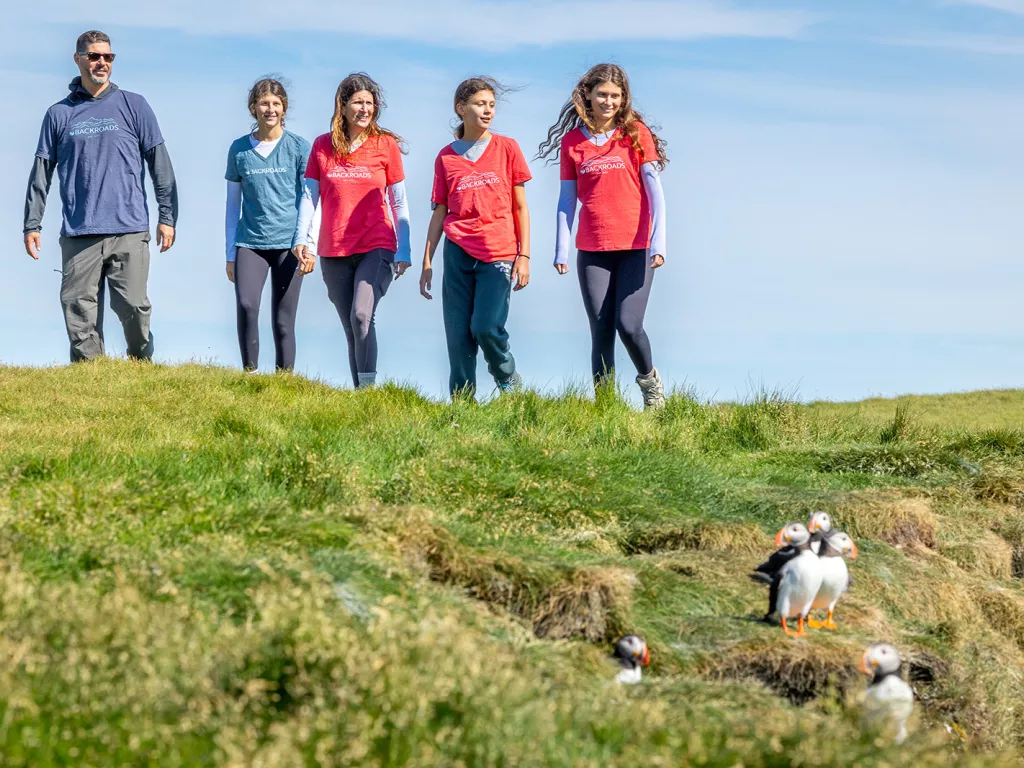 Four women and one man walking on a grassy field