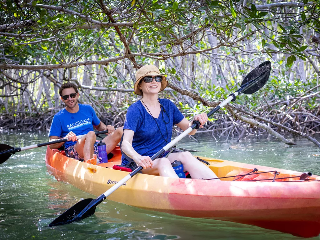 Man and woman paddling on a red and yellow kayak