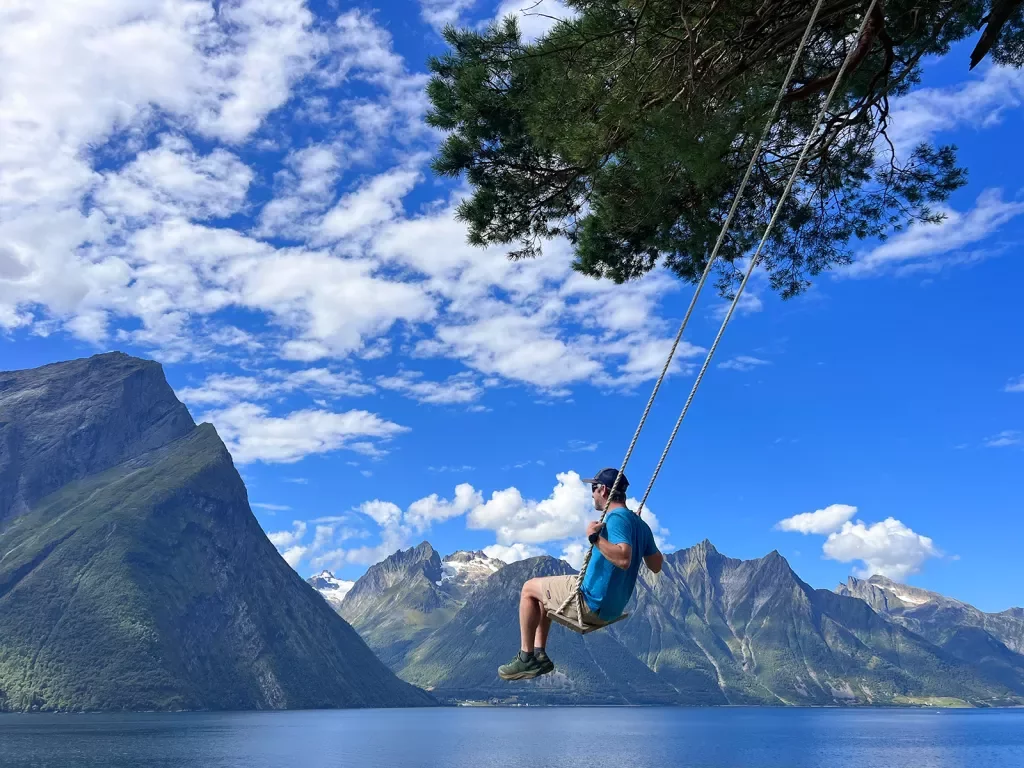 Man sitting on a swing with mountains in the distance